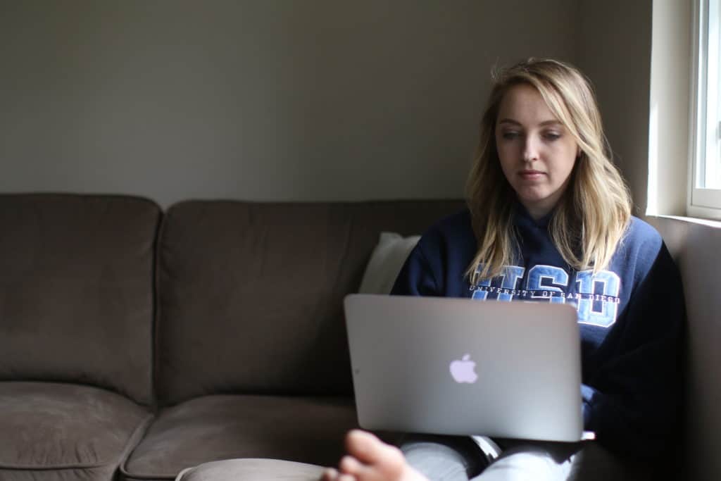 Woman sitting on her couch while using her MacBook Pro