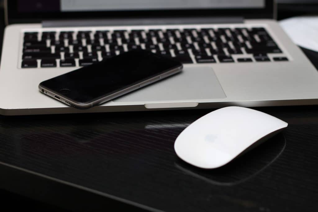 Wireless mouse charging on a laptop with a cellphone placed on top of it
