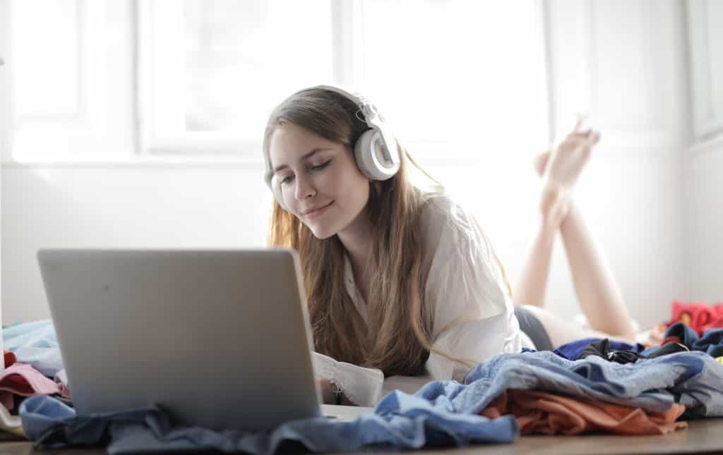 Woman wearing headphones while watching movies in her laptop