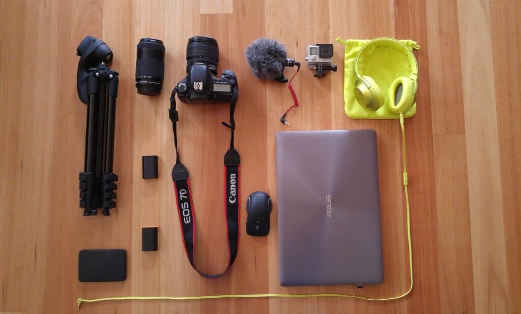 Asus laptop beside a Canon camera, headphones, and other accessories