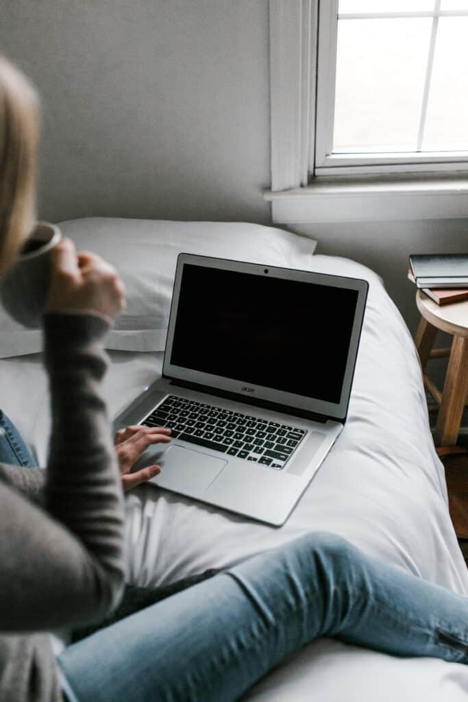 Woman sitting in her bed while using her laptop